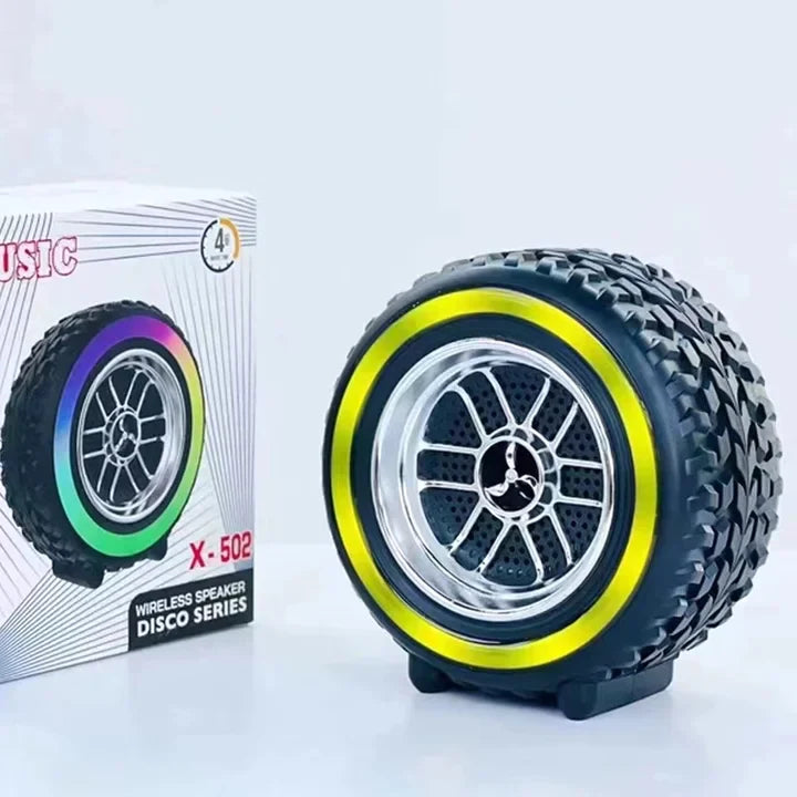 Wireless speaker designed like a tire with a colorful rim, next to its packaging on a white background.