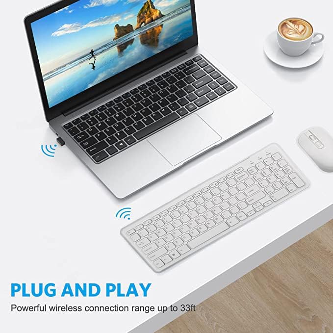 Laptop with wireless keyboard and mouse on a desk, featuring a scenic display.