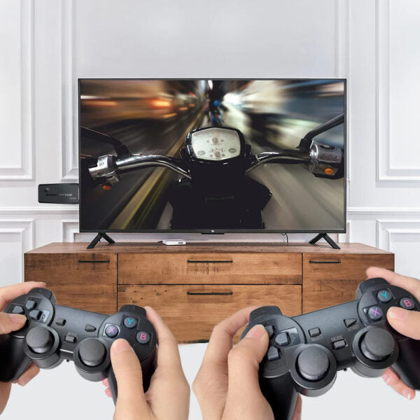 Two pairs of hands holding gaming controllers in front of a television displaying a motorcycle game.