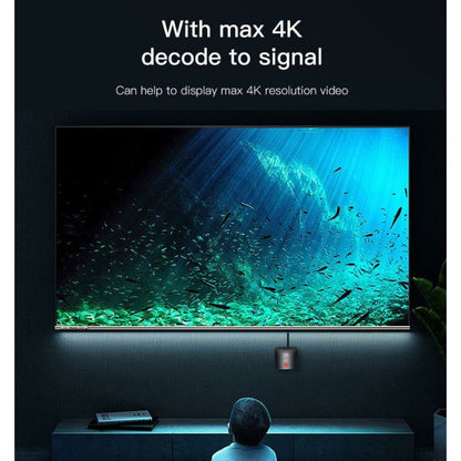 Person watching a large screen displaying an underwater scene with text about 4K resolution.