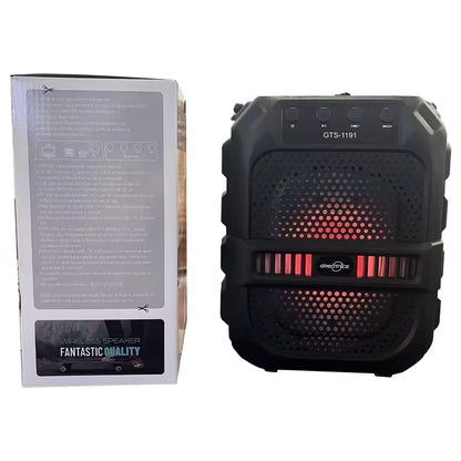 Black wireless speaker with red LED lights next to its packaging on a white background