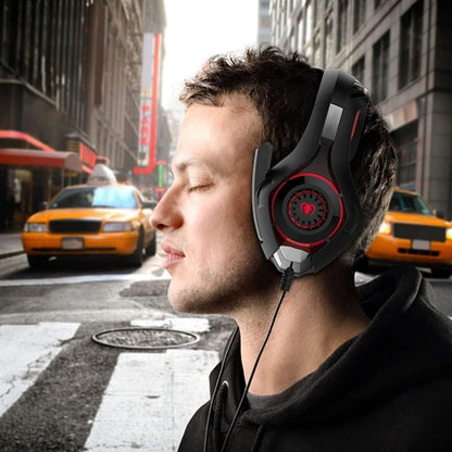 Man wearing a black and red gaming headset on a city street with taxis in the background